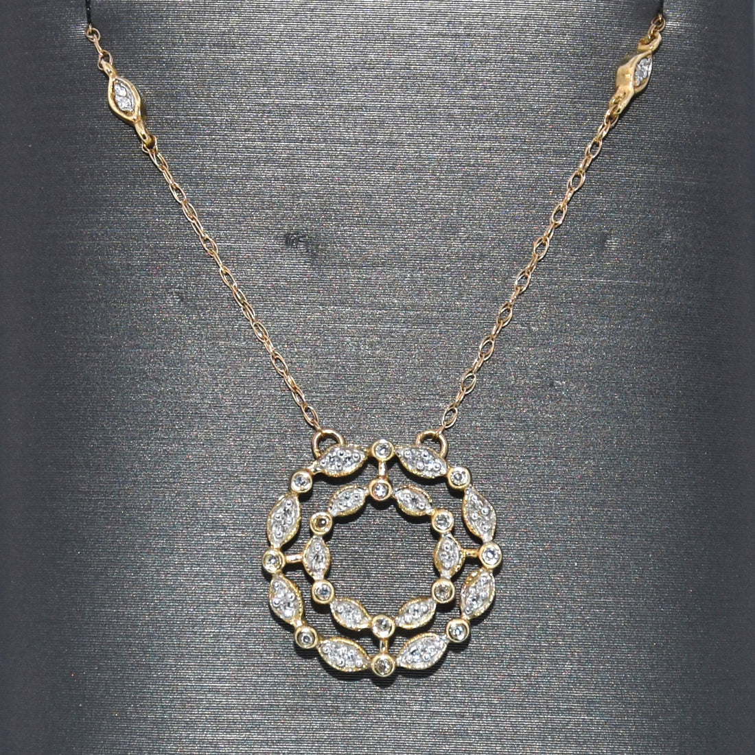 Gold necklace with a circular diamond pendant on a gray background