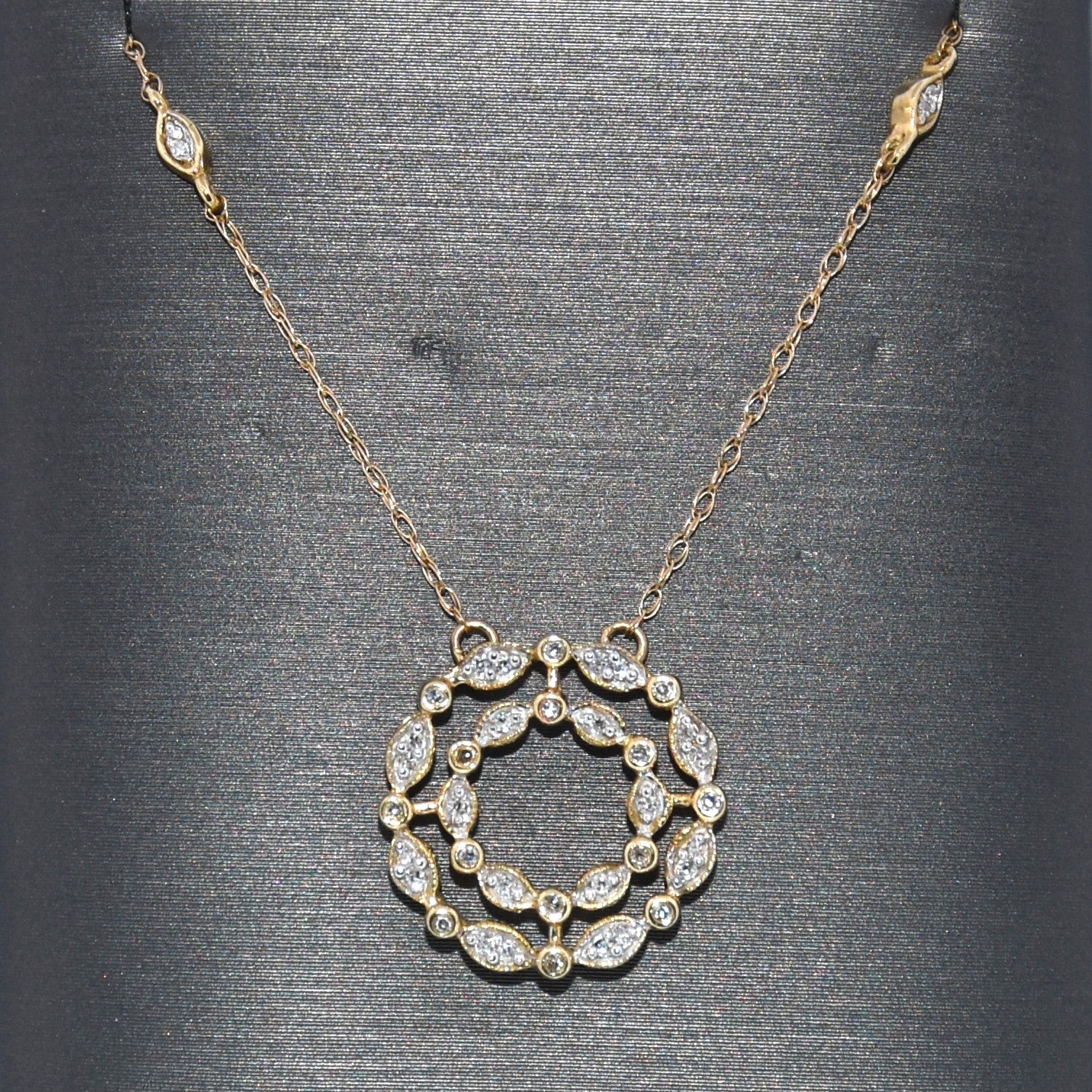 Gold necklace with a circular diamond pendant on a gray background