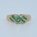 Gold ring with emeralds and diamonds on a light gray background