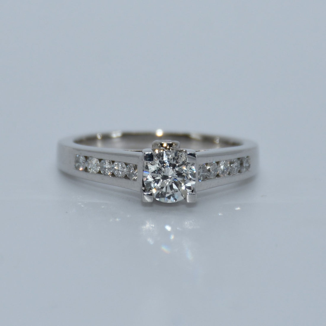 Diamond ring with a white gold band on a light gray background