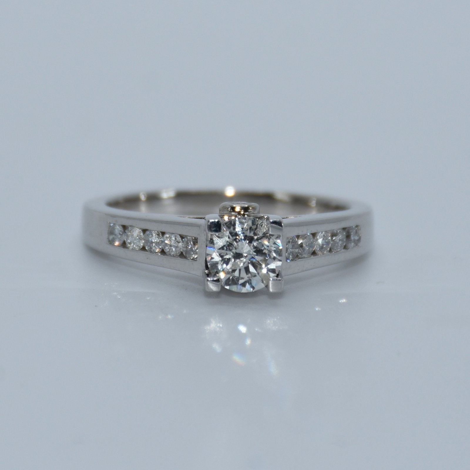 Diamond ring with a white gold band on a light gray background