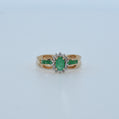 Gold ring with emerald and diamond accents on a light gray background