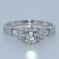 Diamond ring with a central diamond and baguette-cut side stones on a light gray background