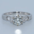 Diamond ring with a central diamond and baguette-cut side stones on a light gray background