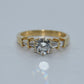 Gold ring with a diamond and baguette-cut gemstones on a light gray background