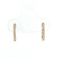 A pair of small gold huggie hoop earrings with a row of clear stones, displayed on a clear plastic jewelry stand against a white background.