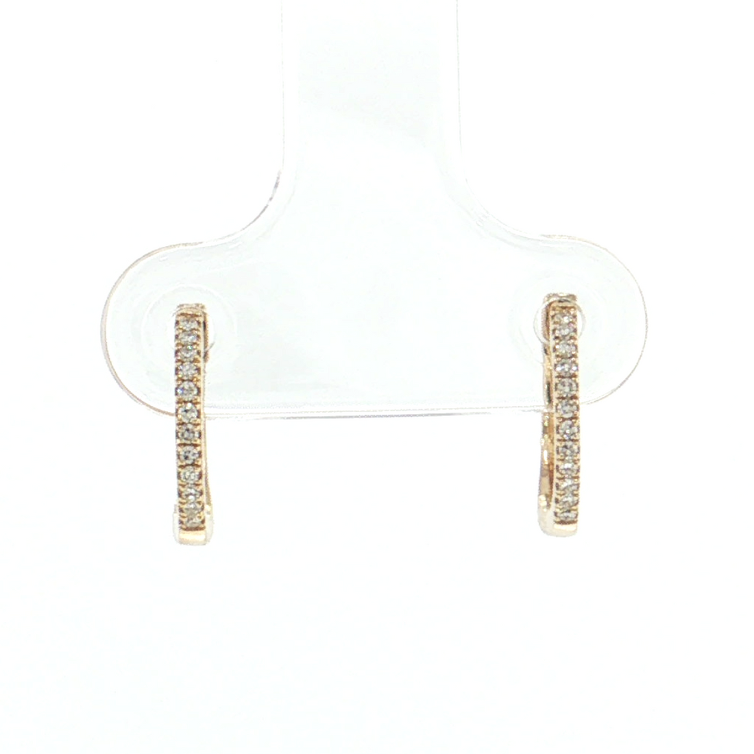 A pair of small gold huggie hoop earrings with a row of clear stones, displayed on a clear plastic jewelry stand against a white background.