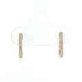 A pair of small gold huggie hoop earrings with a row of clear stones, displayed on a clear plastic jewelry stand against a white background.