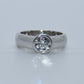 Silver ring with a diamond on a light gray background