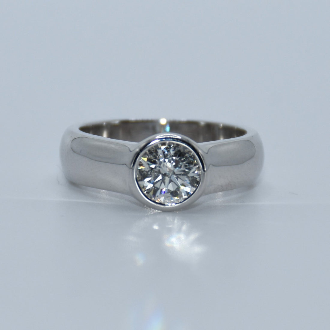 Silver ring with a diamond on a light gray background