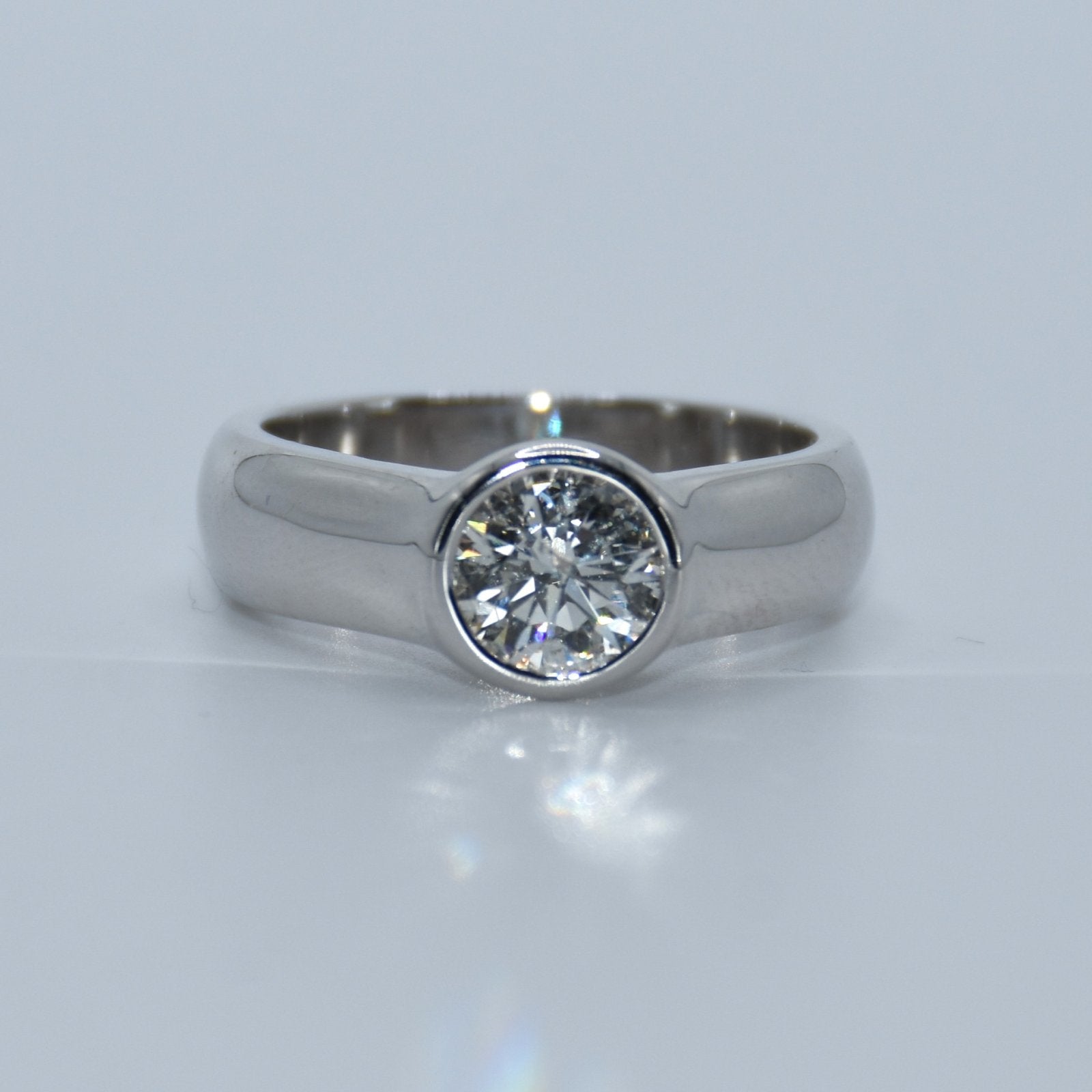 Silver ring with a diamond on a light gray background
