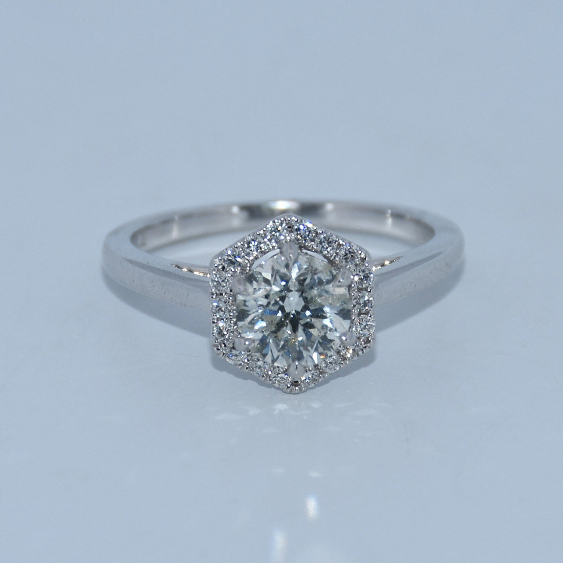 Diamond ring with a hexagonal halo on a light gray background