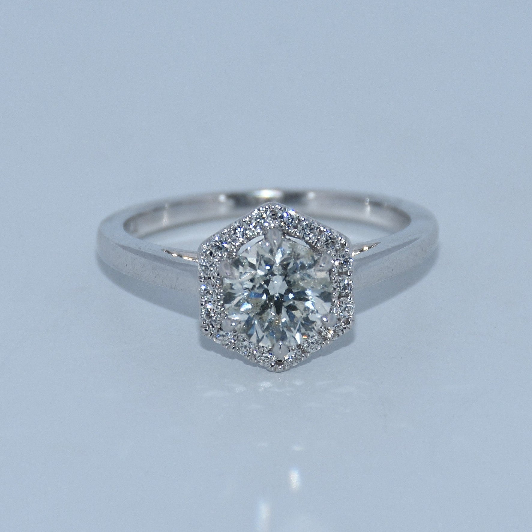 Diamond ring with a hexagonal halo on a light gray background