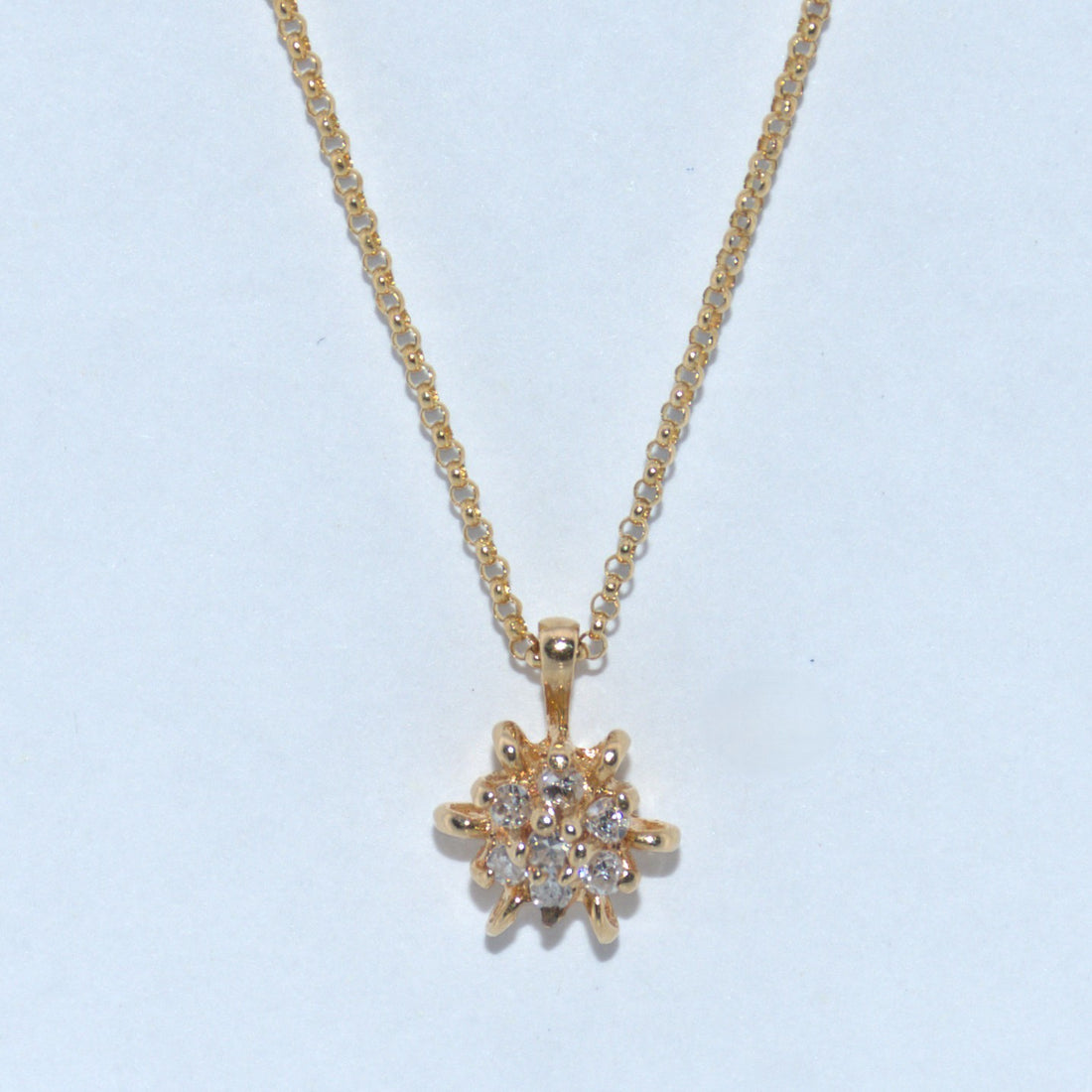 Gold necklace with a star-shaped pendant on a light blue background