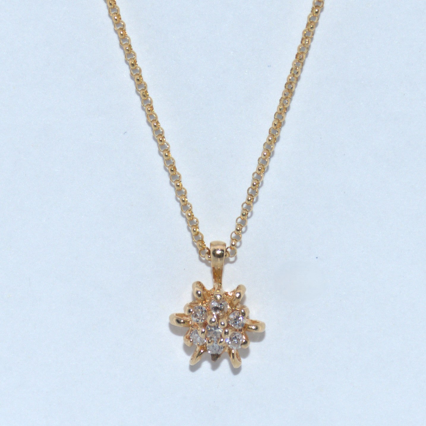 Gold necklace with a star-shaped pendant on a light blue background