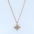 Star-shaped diamond pendant on a rose gold chain against a light blue background