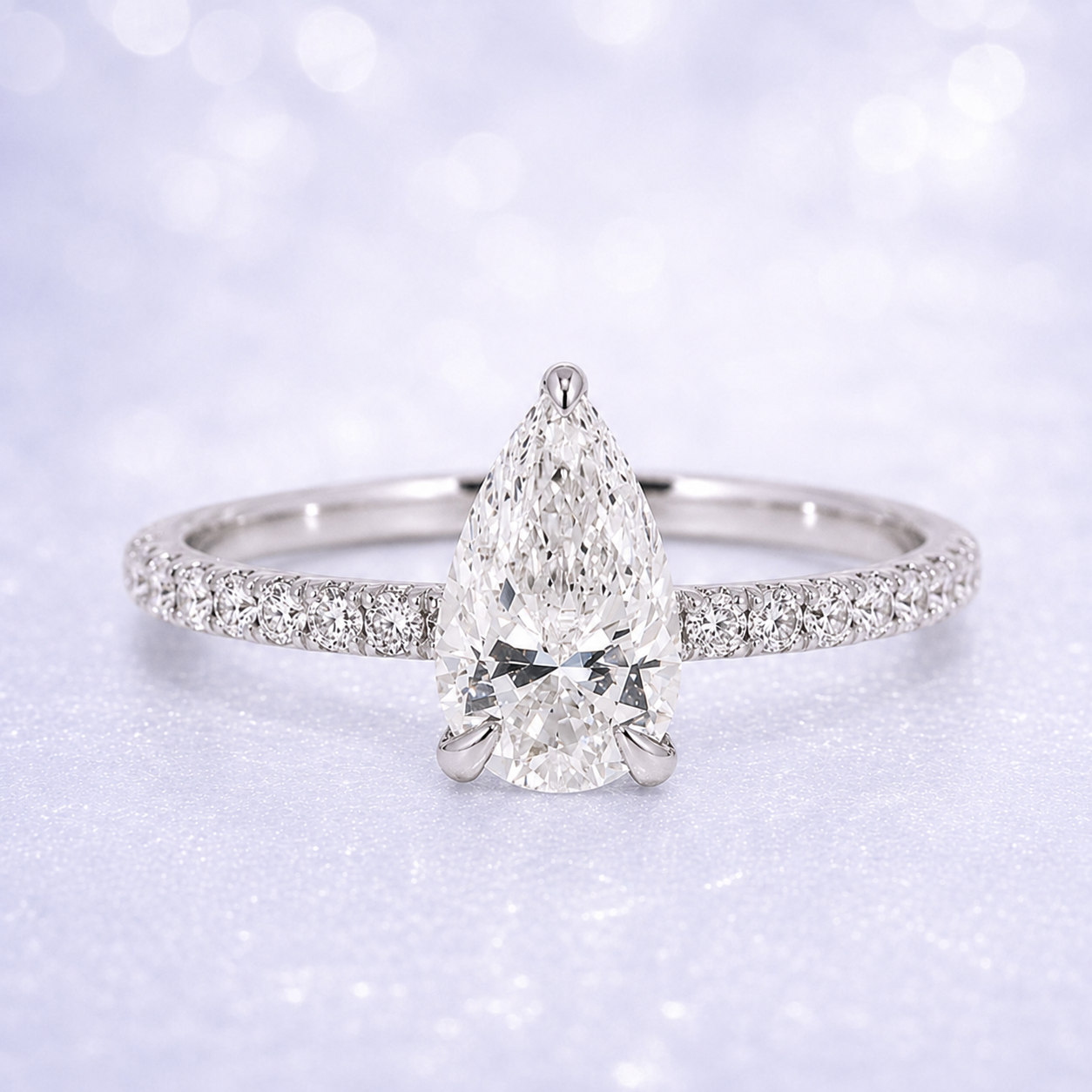 Diamond ring with pear-shaped center stone on a light background 14K Gold | 1CT Pear Lab Grown Diamond Bridal Ring Set with Matching Wedding Band - White Gold
