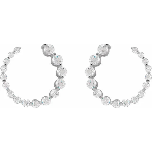 Set of silver hoop earrings with clear gemstones on a white background