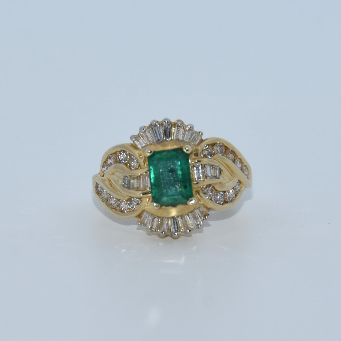 Gold ring with a green gemstone and diamond accents on a white background