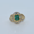 Gold ring with a green gemstone and diamond accents on a white background