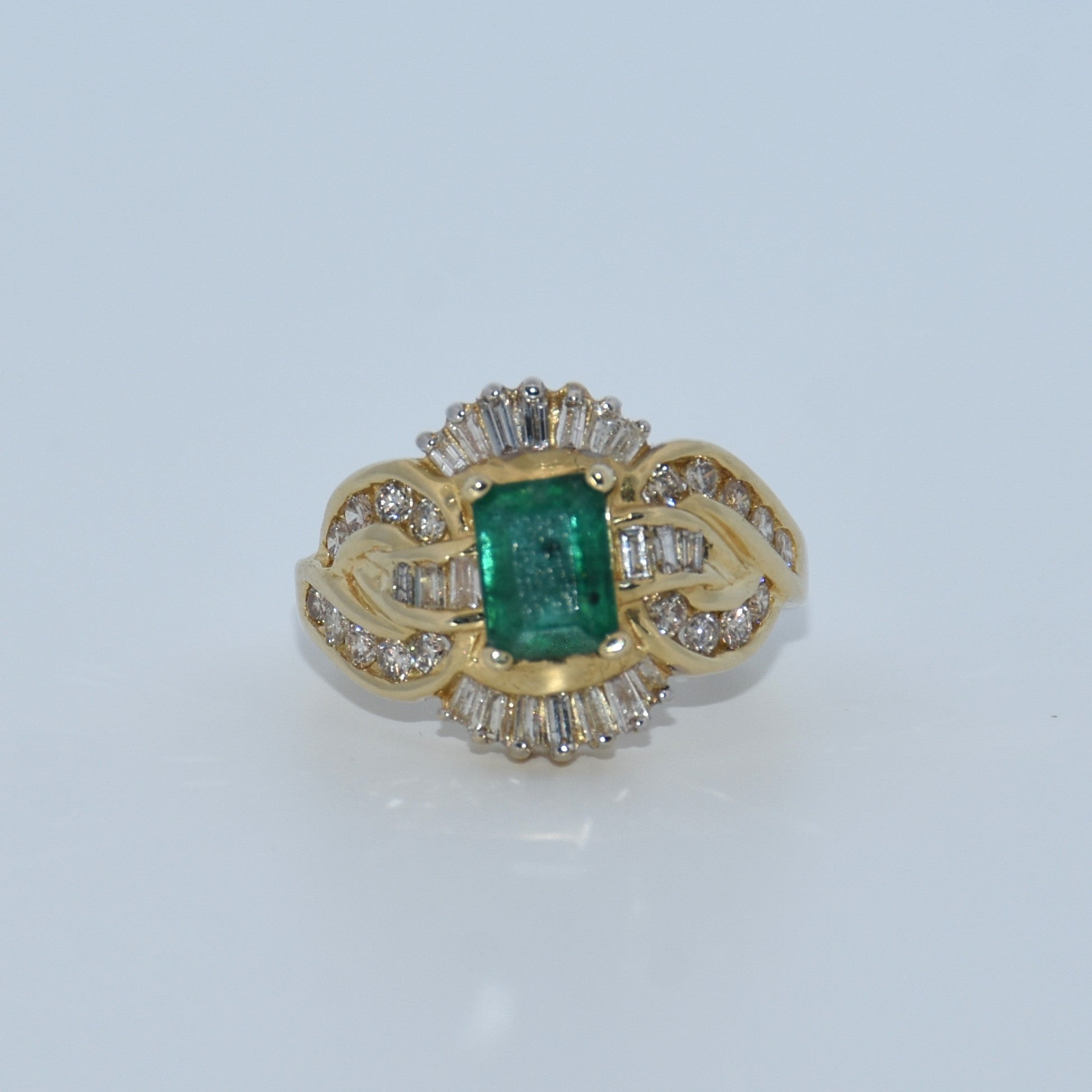Gold ring with a green gemstone and diamond accents on a white background