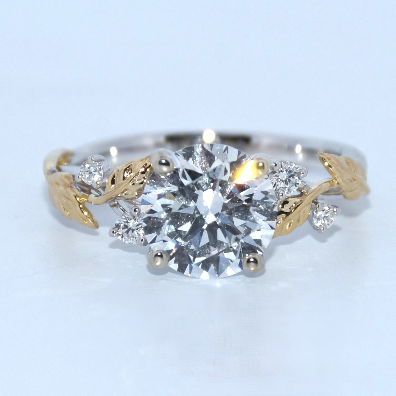 Diamond ring with gold leaf designs on a light gray background