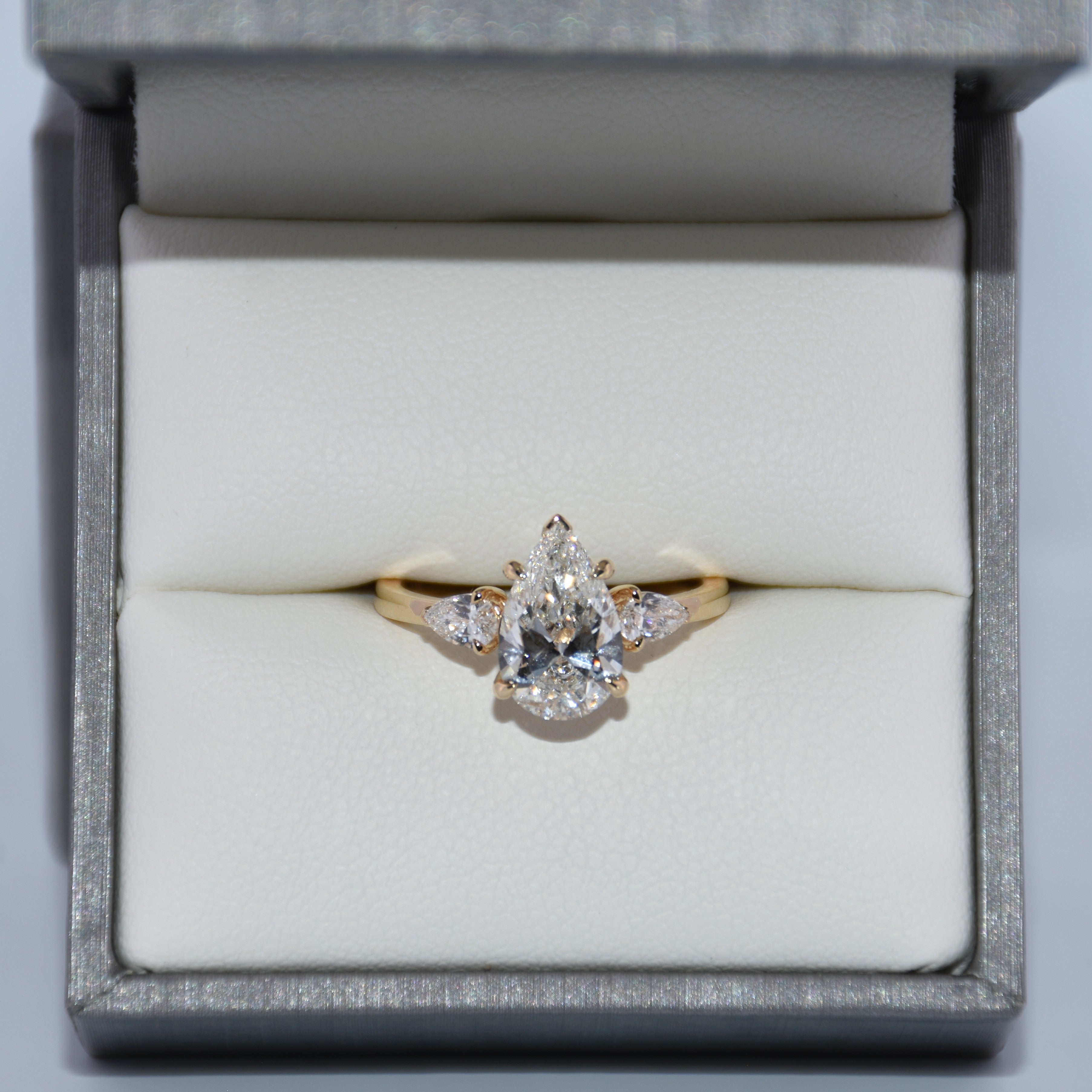 Gold ring with a diamond in a jewelry box on a light gray background