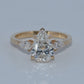 Gold ring with a central diamond and smaller diamonds on a light gray background