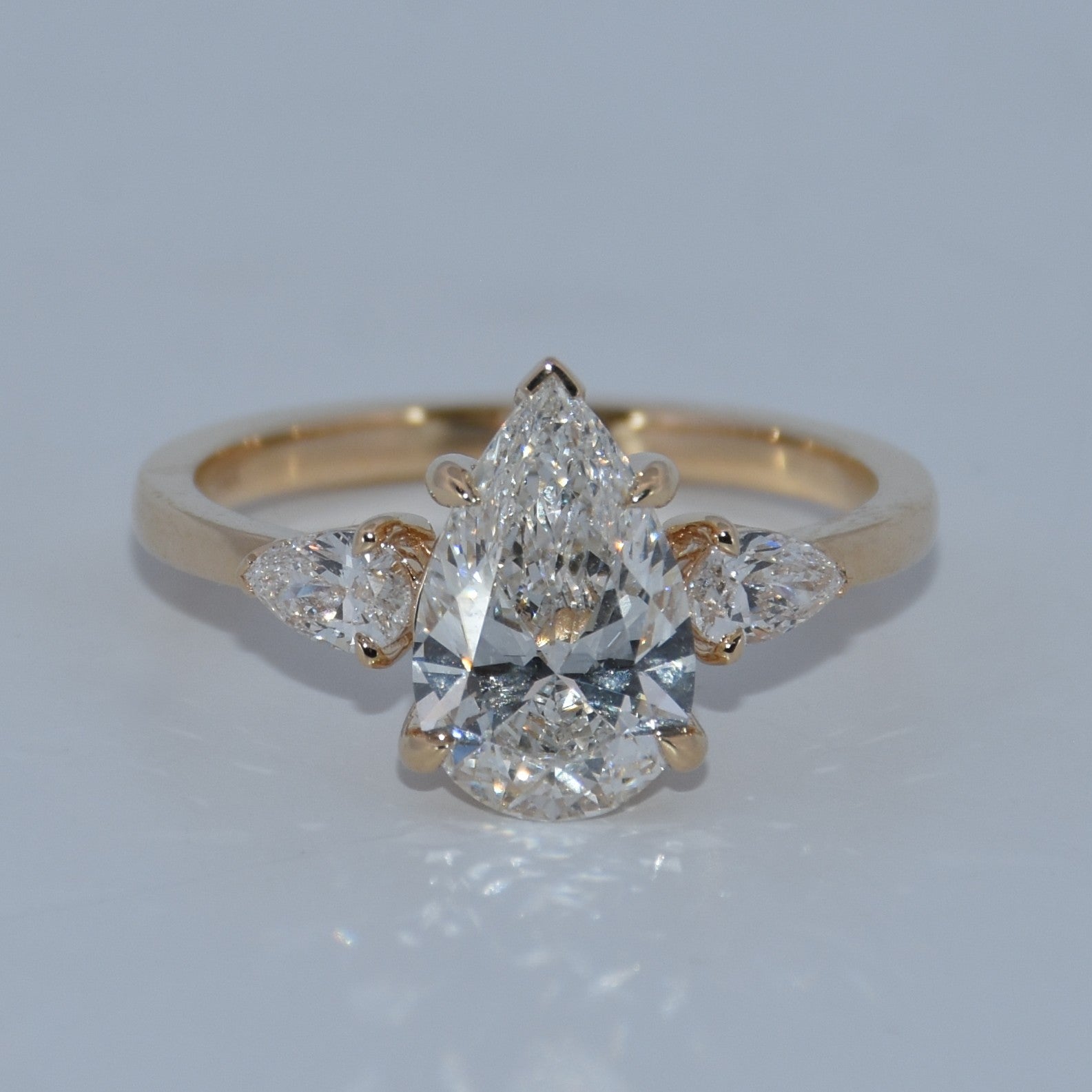 Gold ring with a central diamond and smaller diamonds on a light gray background