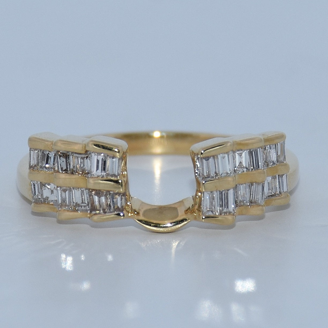Gold ring with diamond accents on a reflective surface