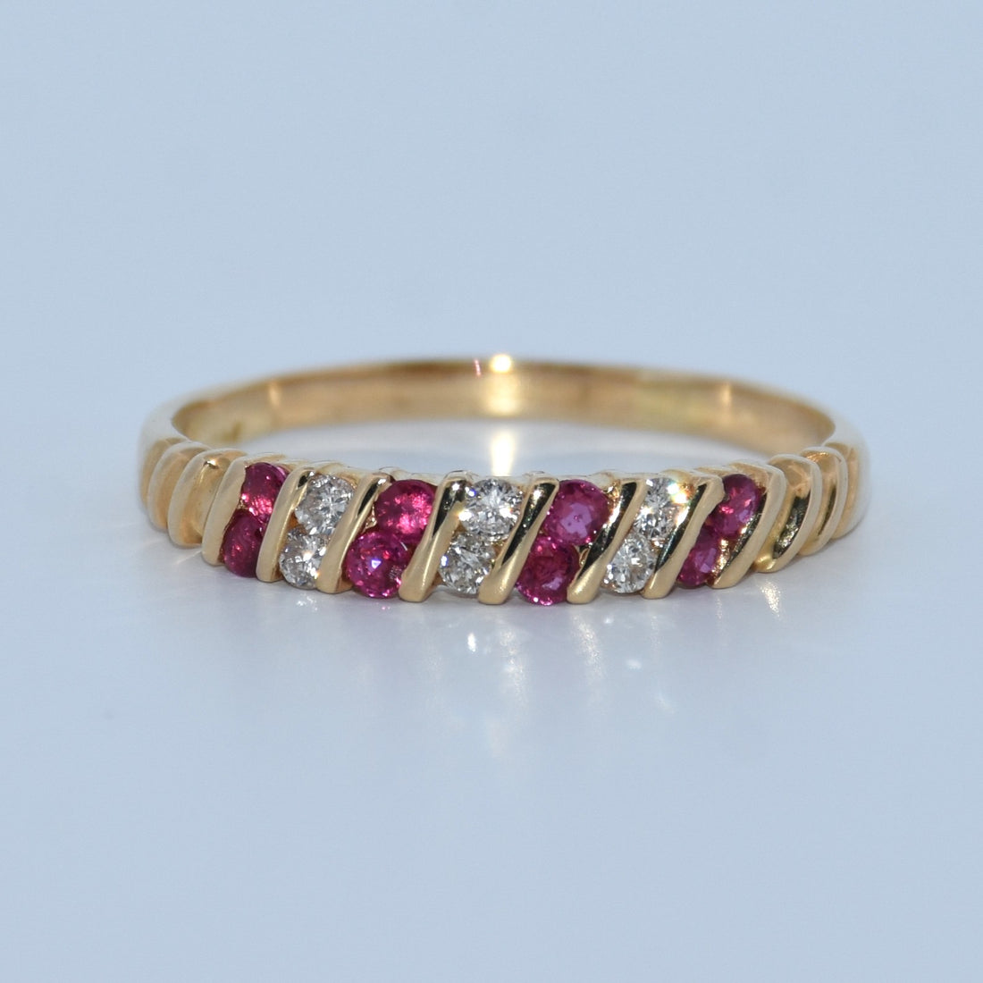 Gold ring with red gemstones and clear stones on a light gray background