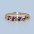 Gold ring with red gemstones and clear stones on a light gray background