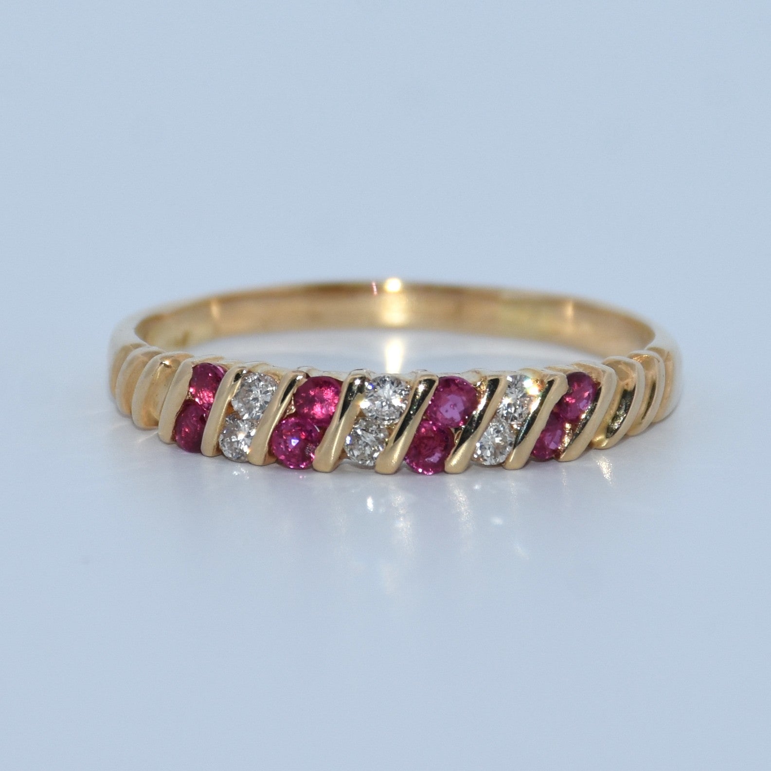 Gold ring with red gemstones and clear stones on a light gray background