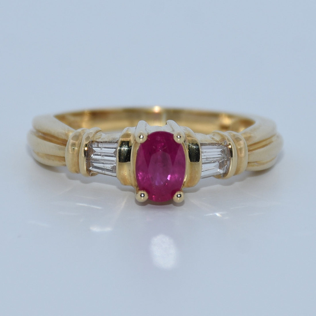 Gold ring with a pink gemstone and diamond-like stones on a white background