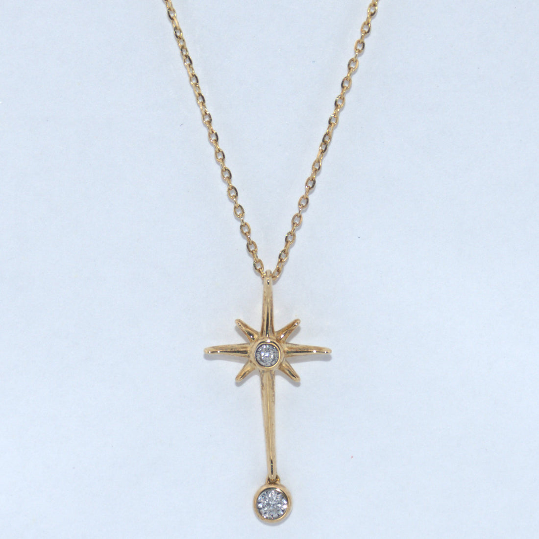 Gold necklace with star-shaped pendant on a light blue background