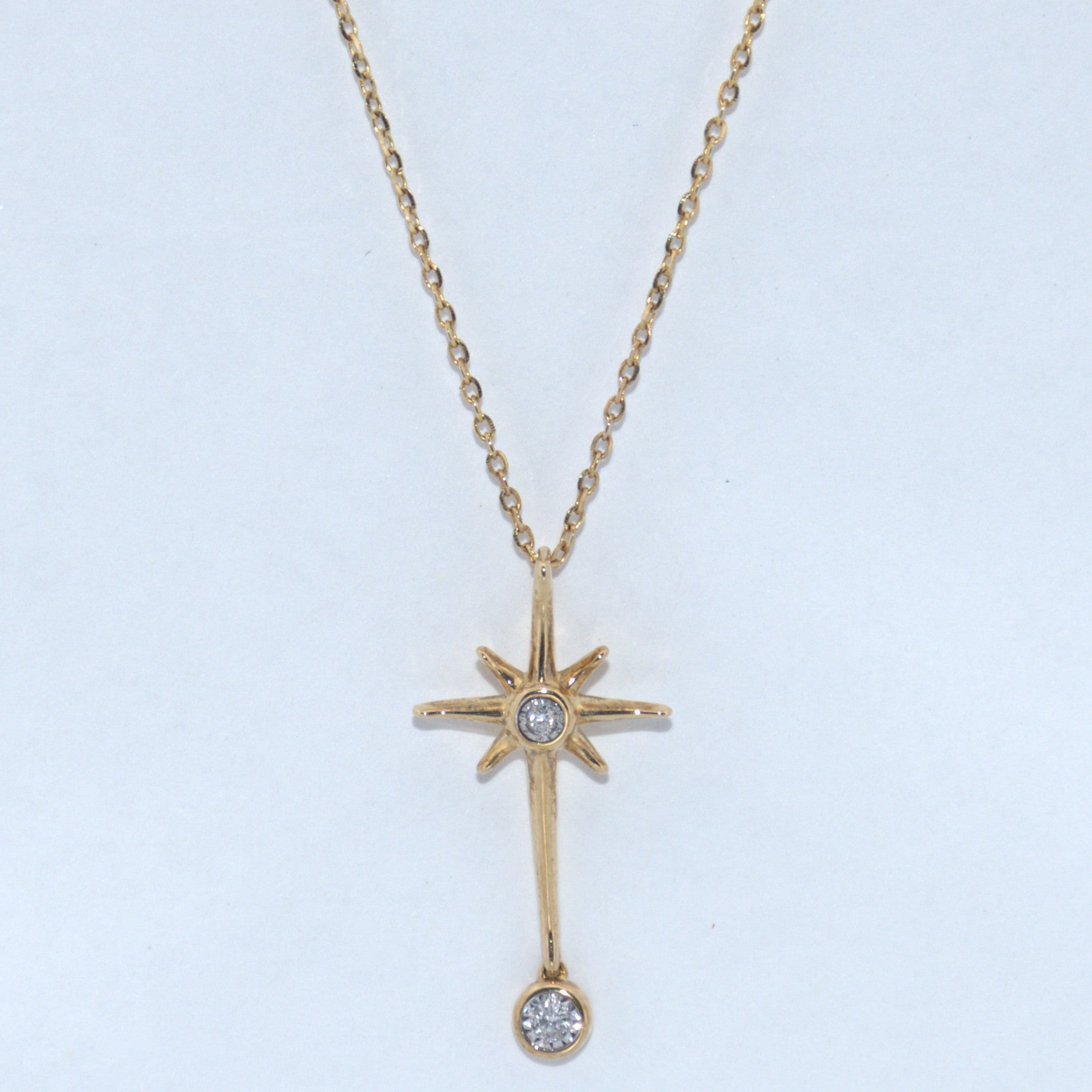 Gold necklace with star-shaped pendant on a light blue background