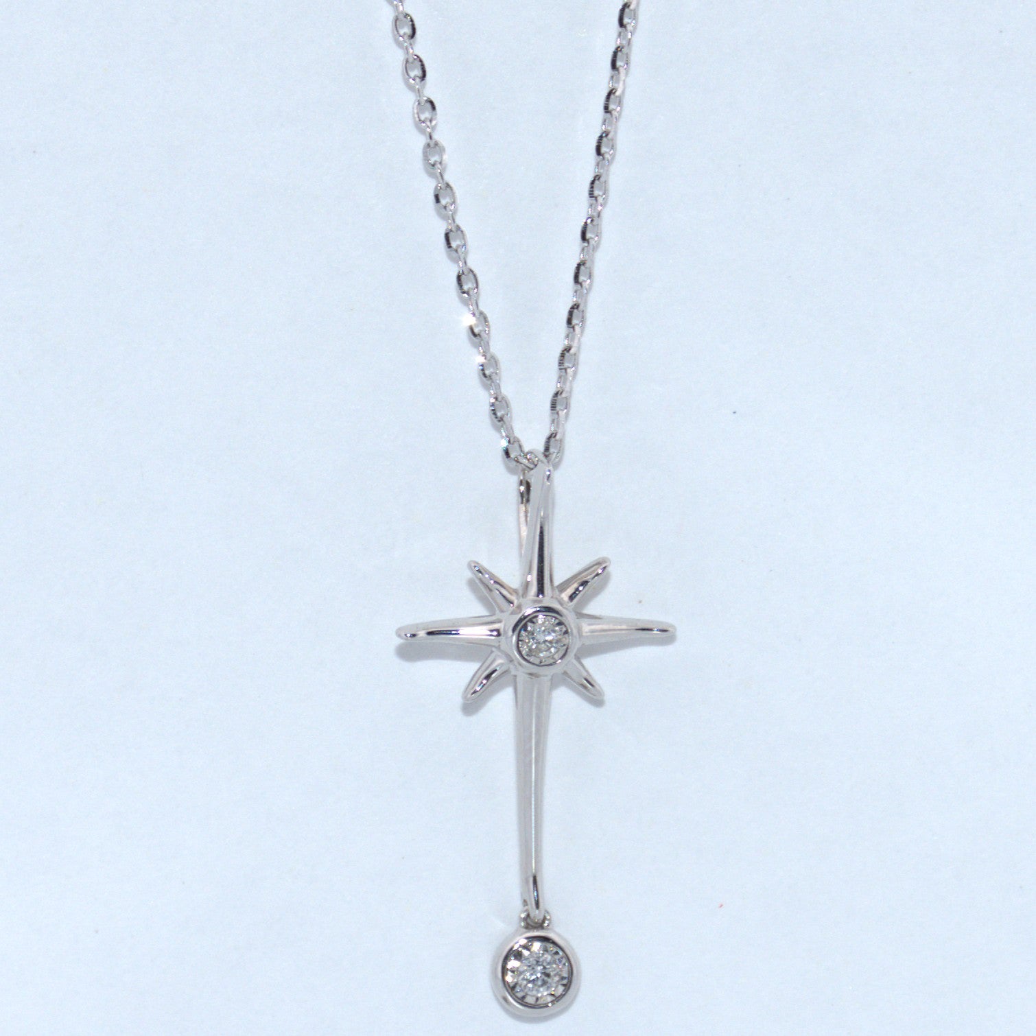 Silver star-shaped pendant necklace with two small diamonds on a light blue background
