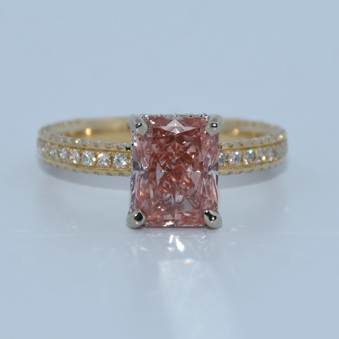 Ring with a pink diamond and gold band on a light gray background