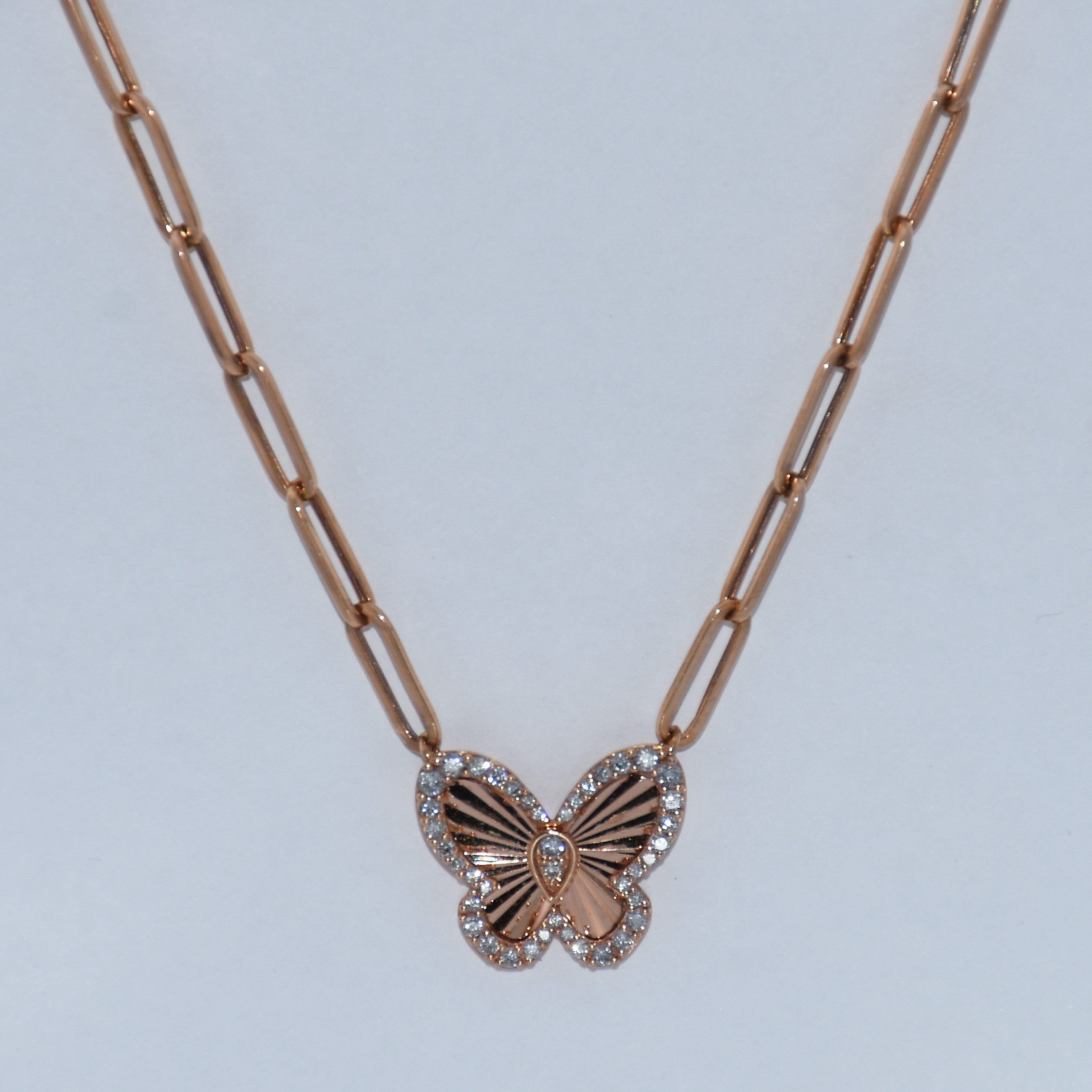 Rose gold butterfly necklace on a light gray background