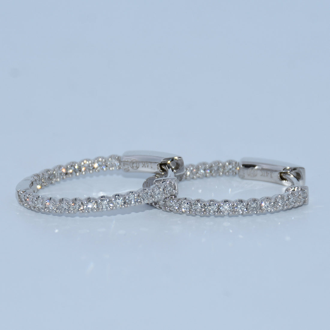 Pair of silver hoop earrings on a light blue background
