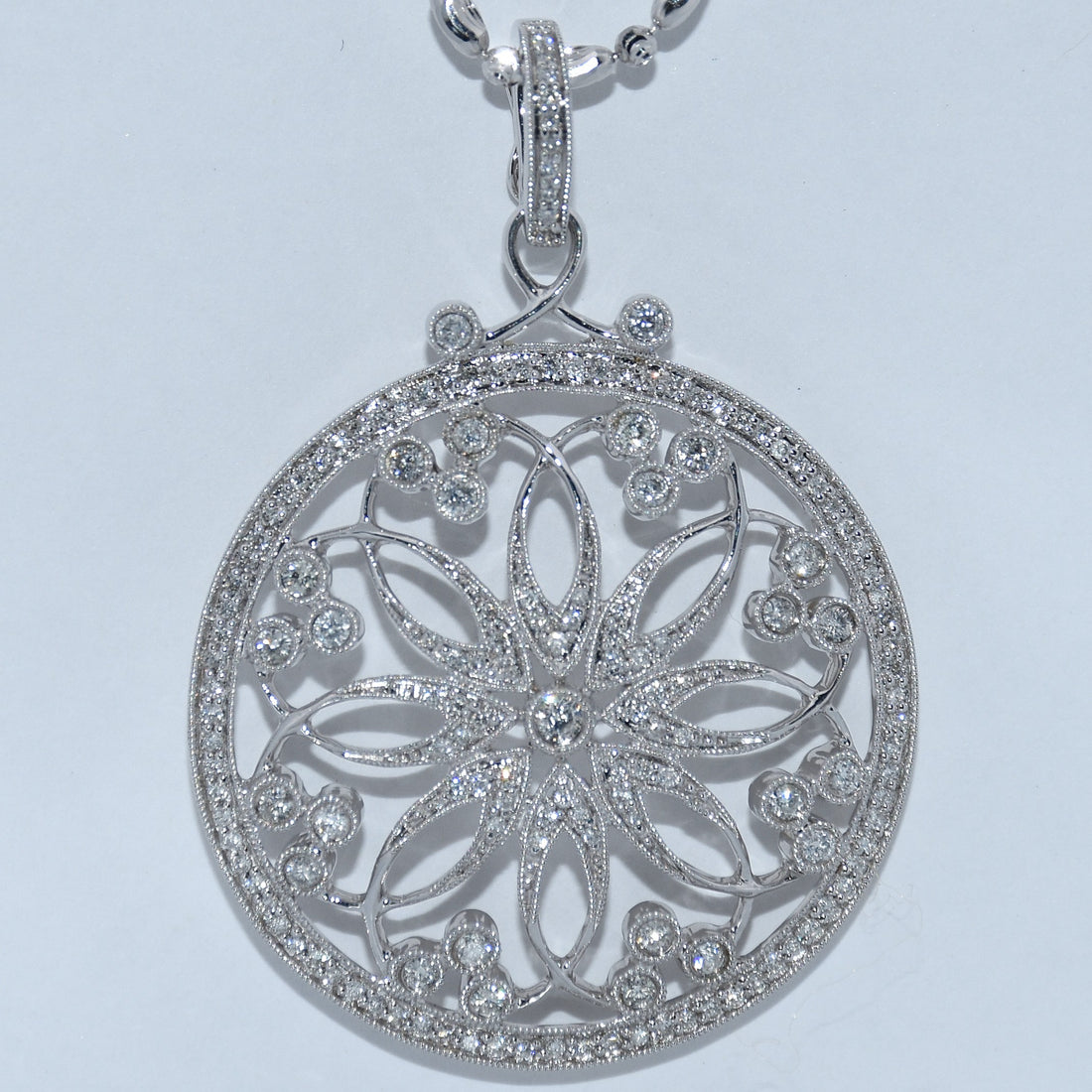 Silver floral pendant with clear stones on a light gray background