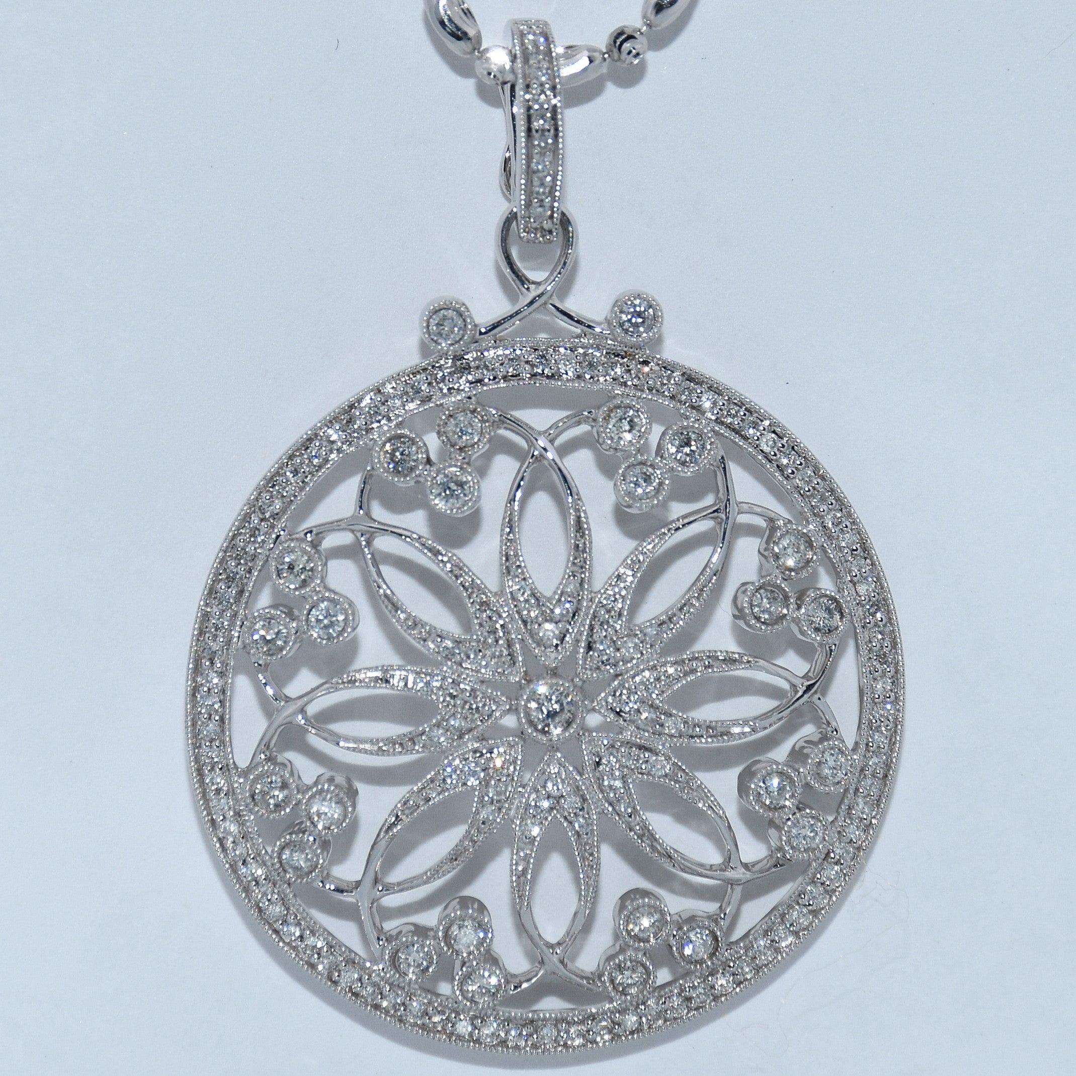 Silver floral pendant with clear stones on a light gray background
