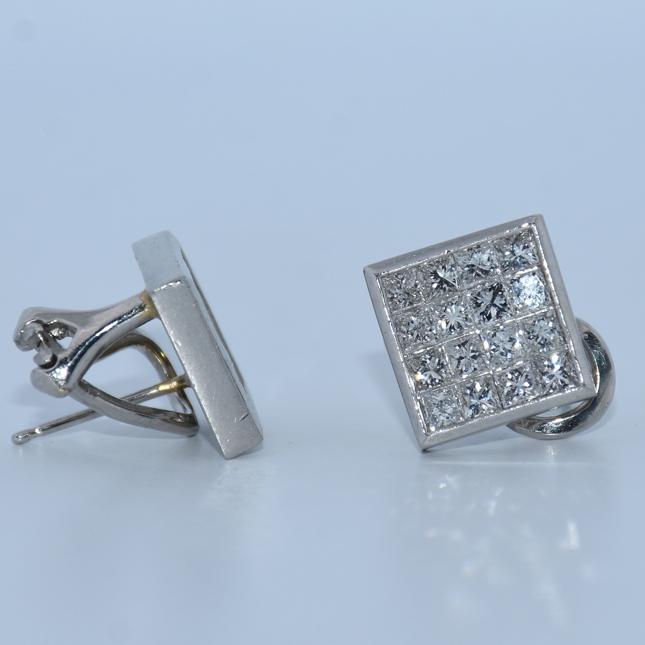 Pair of silver cufflinks with one square and one rectangular design on a light gray background