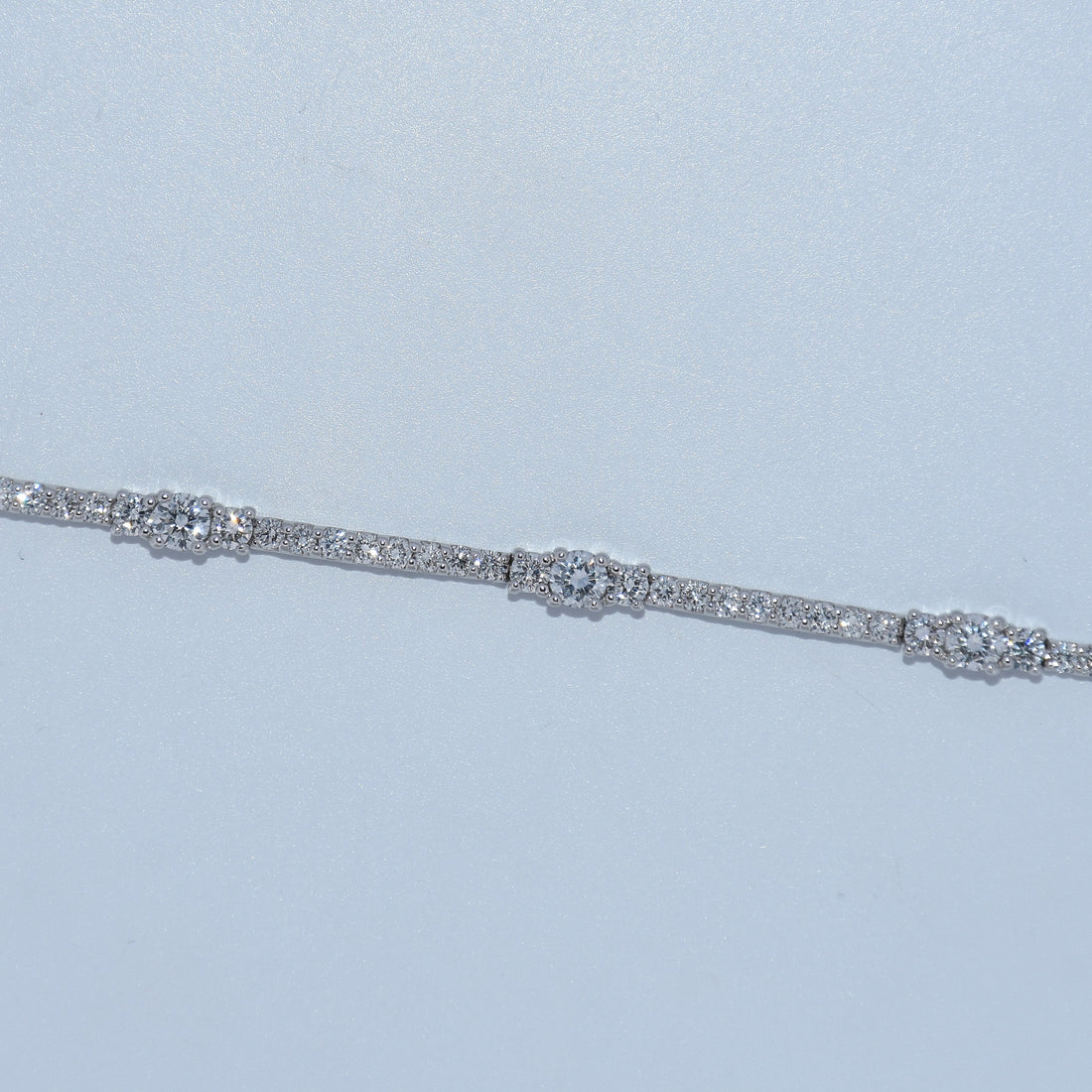 Silver bracelet with clear stones on a light blue background