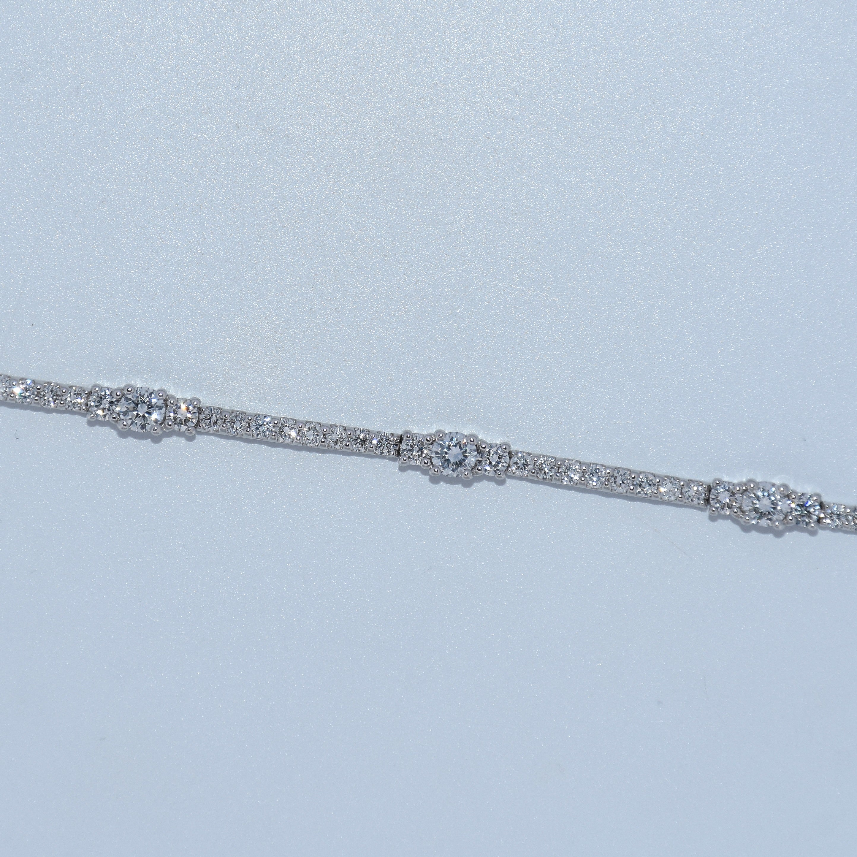 Silver bracelet with clear stones on a light blue background