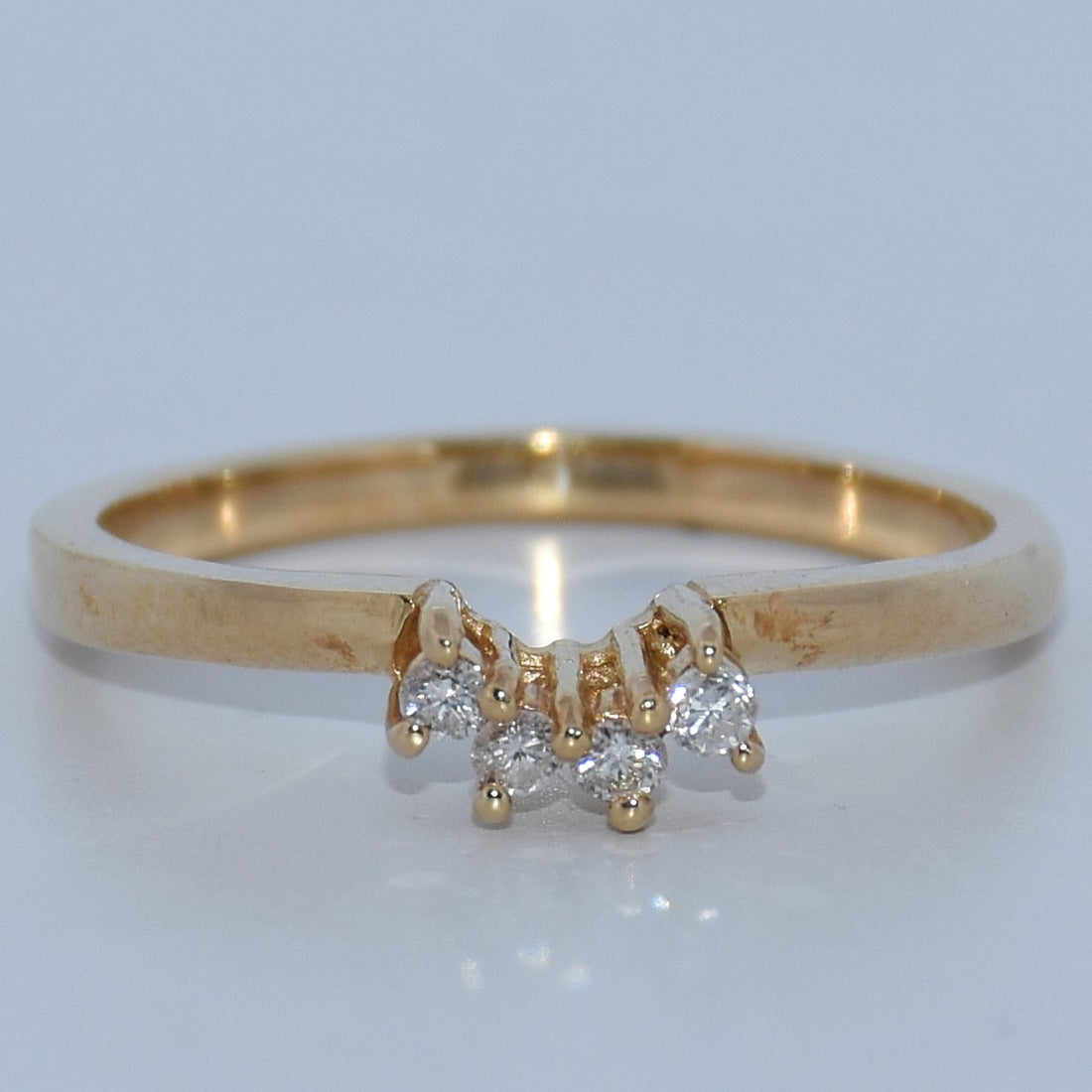 Gold ring with diamond accents on a light gray background