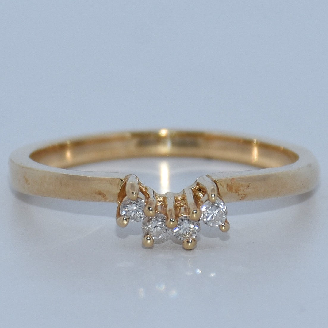 Gold ring with diamond accents on a light gray background