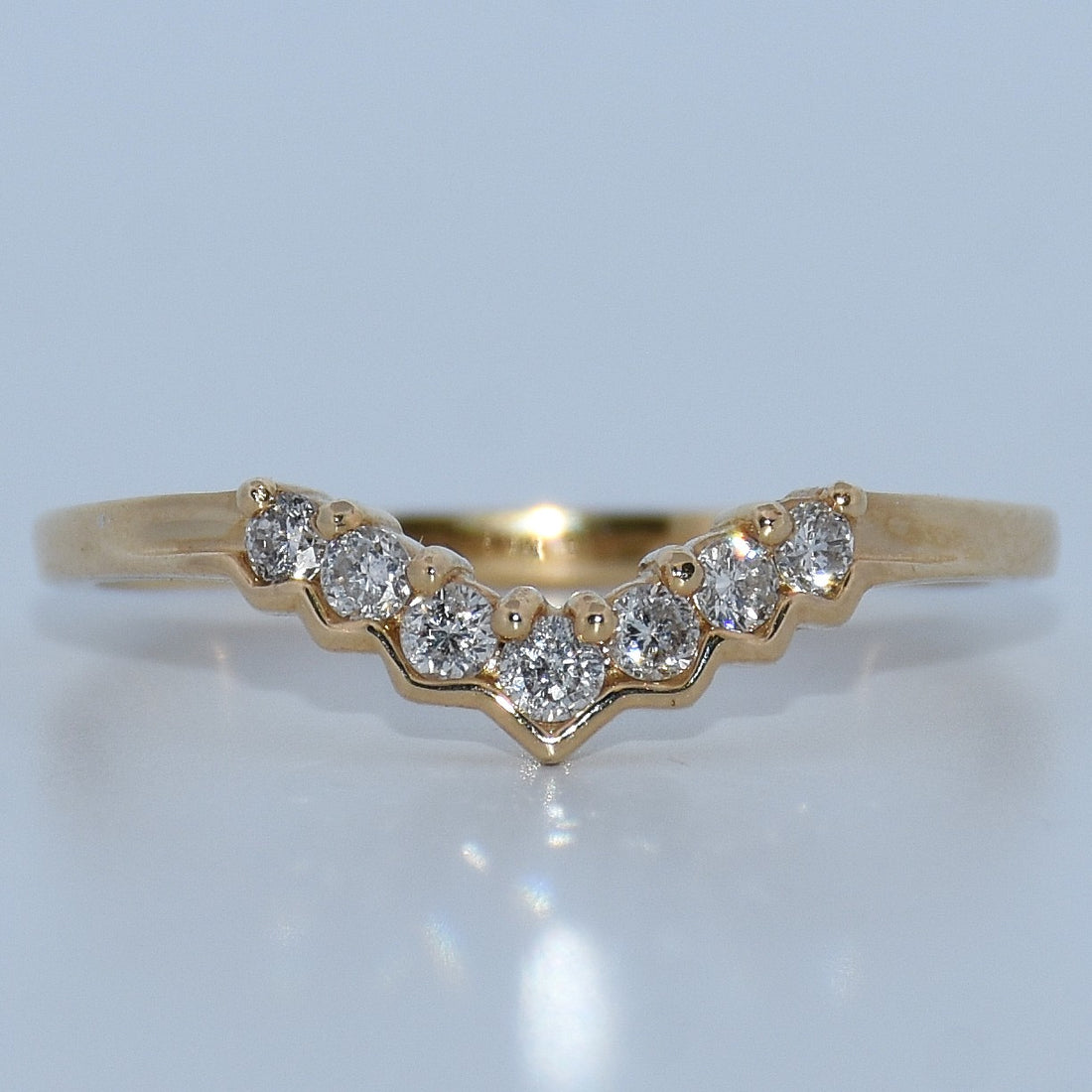 Gold ring with diamonds on a light gray background