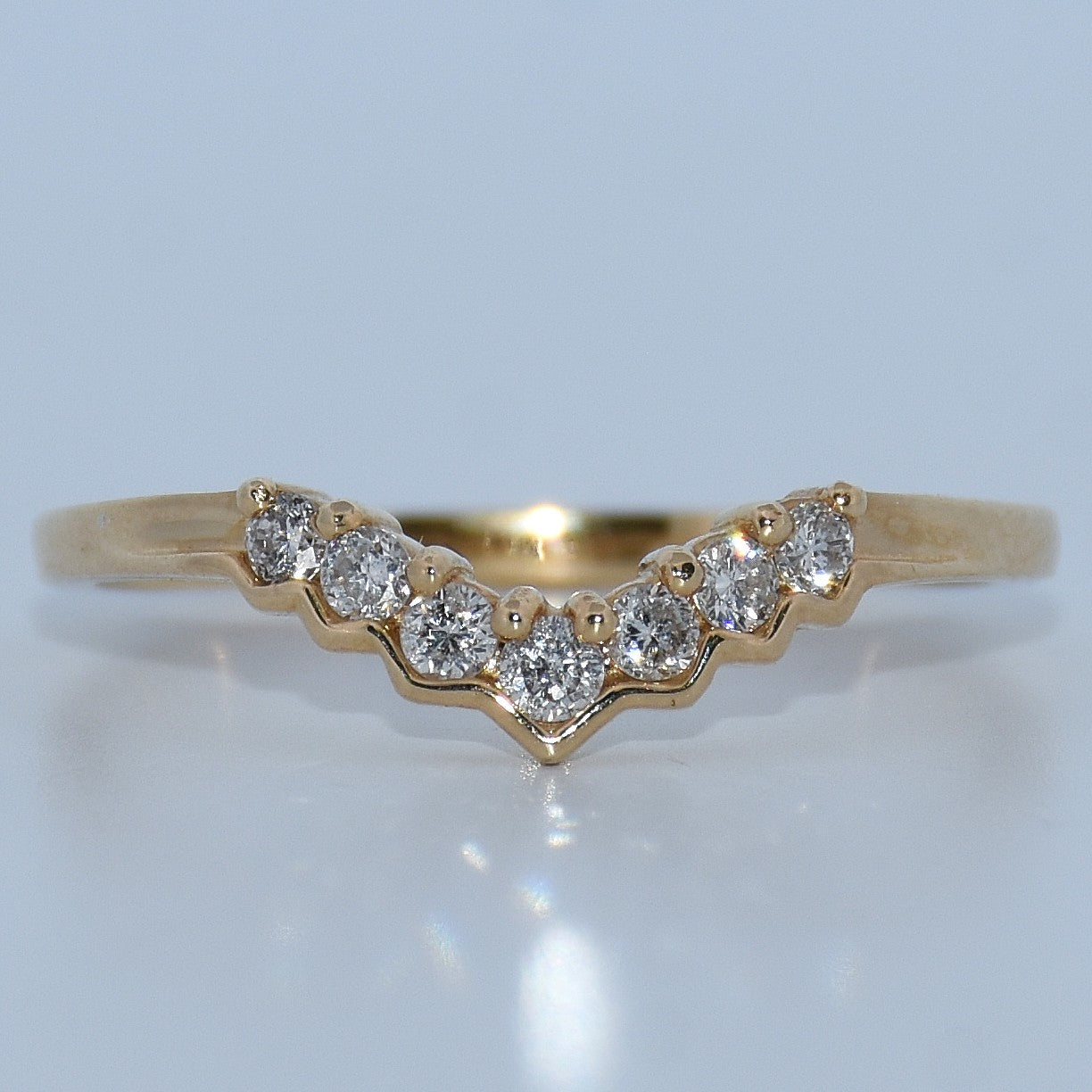 Gold ring with diamonds on a light gray background