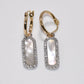 Pair of gold hoop earrings with rectangular gemstones on a light gray background